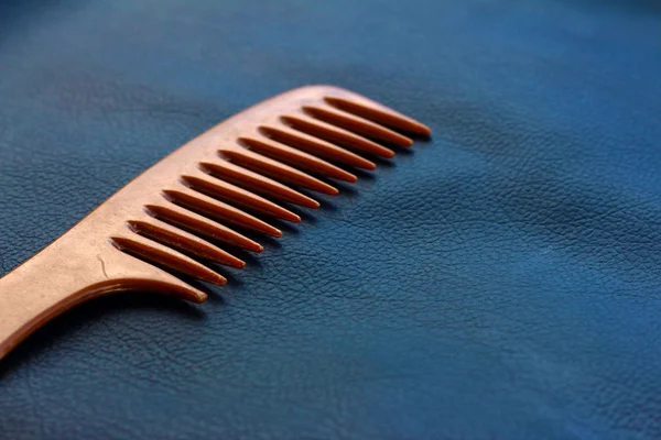 A wooden comb on a nevy blue background