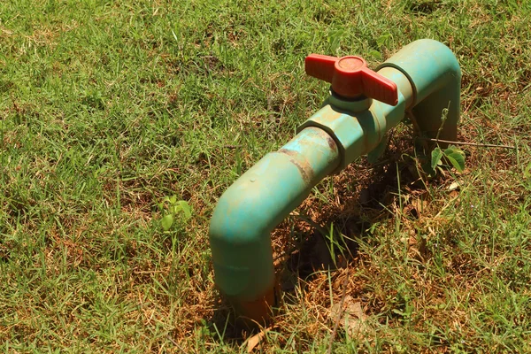 Uma tubulação de água na grama verde — Fotografia de Stock