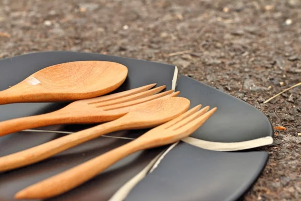 Spoon and fork on a crack  black plate. — Stock Photo, Image