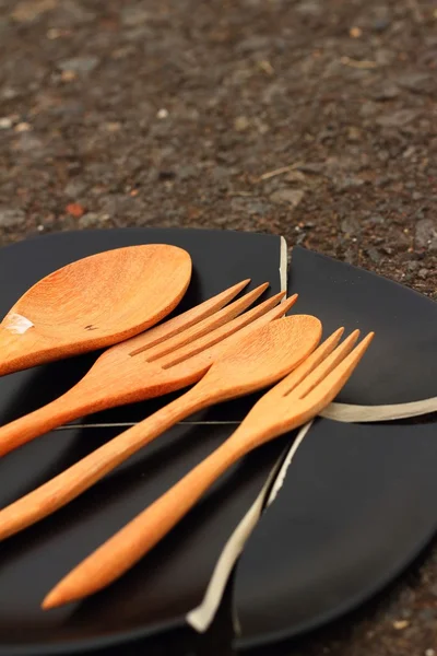 Spoon and fork on a crack  black plate. — Stock Photo, Image