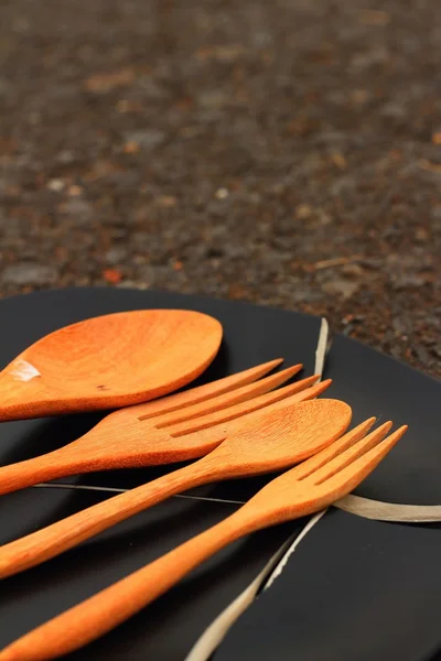 Spoon and fork on a crack  black plate. — Stock Photo, Image