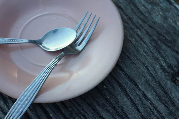 Löffel und Gabel auf einem rosa Teller — Stockfoto