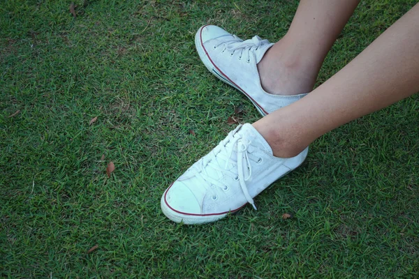 Chaussures blanches sur fond d'herbe verte . — Photo