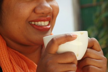 Siyah bir gömlek giymiş kadın kahve içiyor.