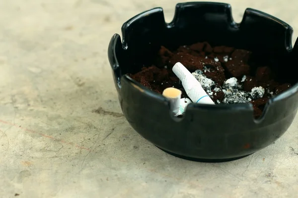Cigarette dans le cendrier sur le sol de ciment . — Photo