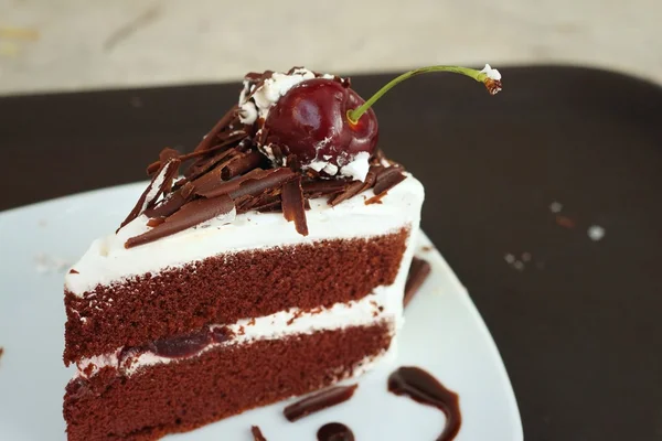 Chocolate cake with cherries on white dish. — Stock Photo, Image