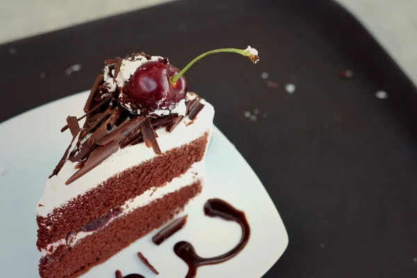 Chocolate cake with cherries on white dish. — Stock Photo, Image
