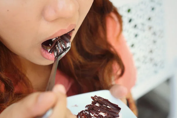 Mulher comendo bolo de chocolate em um café . — Fotografia de Stock