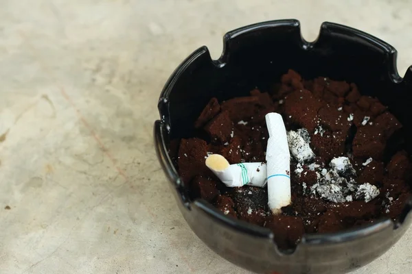 Cigarette dans le cendrier sur le sol de ciment . — Photo