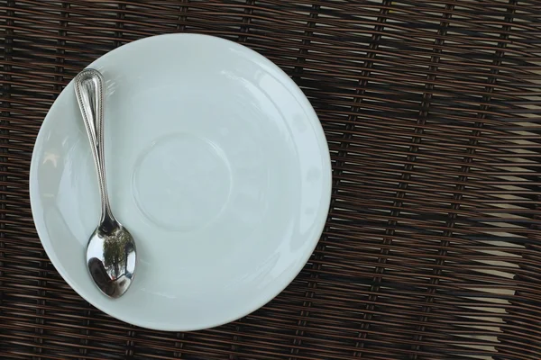 Белое блюдо с ложкой на коричневом фоне . — стоковое фото