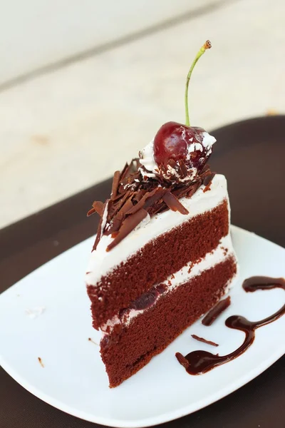 Chocolate cake with cherries on white dish. — Stock Photo, Image