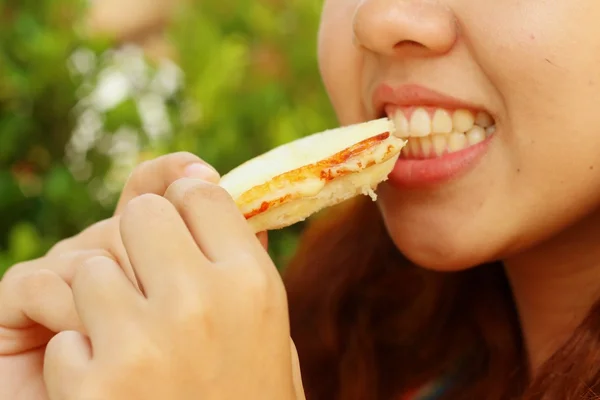 Mulher comendo um sanduíche com presunto e queijo . — Fotografia de Stock