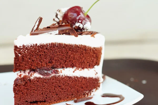 Chocolate cake with cherries on white dish. — Stock Photo, Image