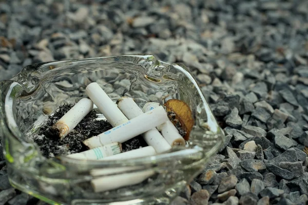 Cigarette in the ashtray on a stone floor. — Stock Photo, Image