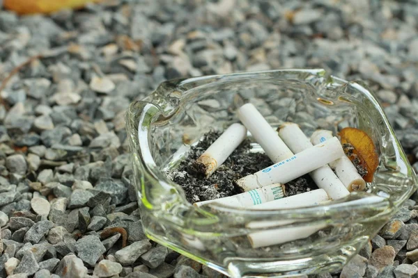 Cigarette in the ashtray on a stone floor. — Stock Photo, Image