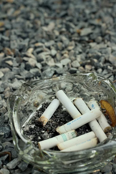 Cigarette in the ashtray on a stone floor. — Stock Photo, Image