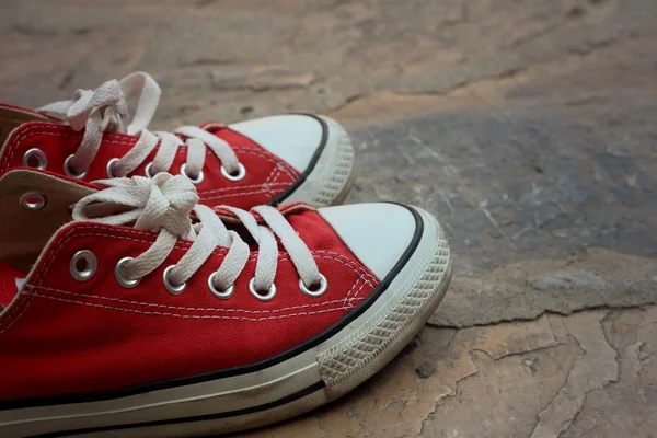 Röda skor på bakgrund av cement. — Stockfoto