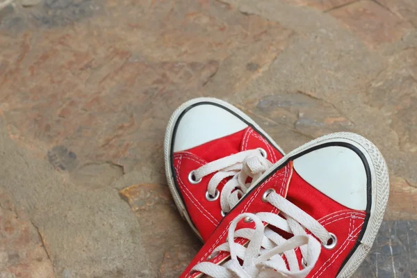 Röda skor på bakgrund av cement. — Stockfoto