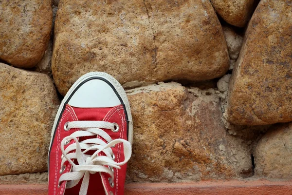Kahverengi taş zemin üzerine kırmızı ayakkabılar.