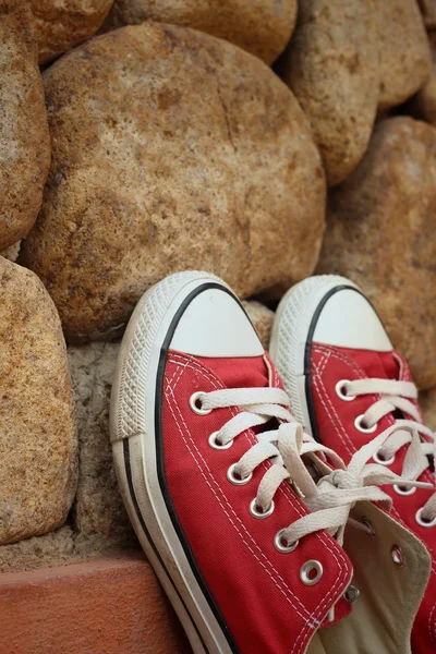 Rote Schuhe auf einem Hintergrund aus braunem Stein. — Stockfoto