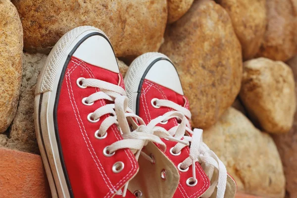 Rote Schuhe auf einem Hintergrund aus braunem Stein. — Stockfoto