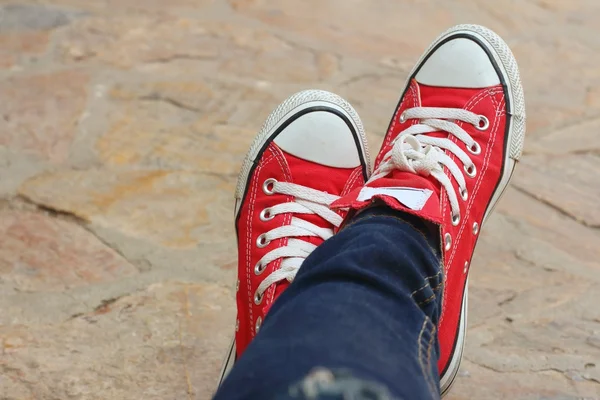 Rote Schuhe auf dem Hintergrund des Zements. Stockbild