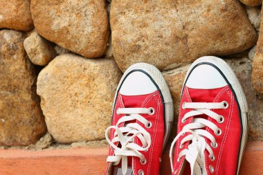 Kahverengi taş zemin üzerine kırmızı ayakkabılar.