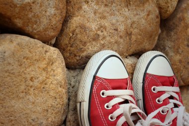 Kahverengi taş zemin üzerine kırmızı ayakkabılar.