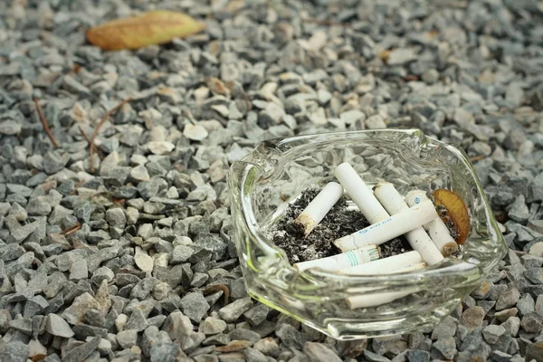 Cigarette in the ashtray on a stone floor. — Stock Photo, Image