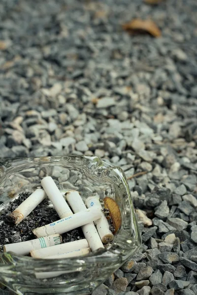 Cigarette in the ashtray on a stone floor. — Stock Photo, Image