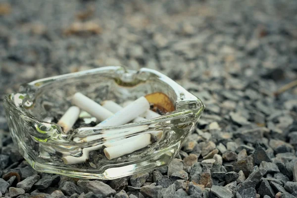 Cigarette in the ashtray on a stone floor. — Stock Photo, Image