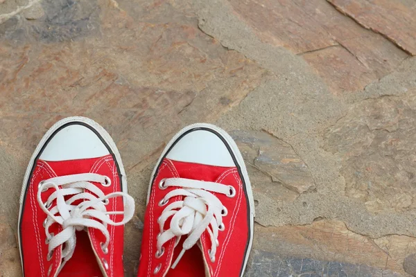 Çimento zemin üzerine kırmızı ayakkabılar.