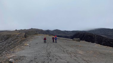 Kamçatka 'nın merkezindeki lav tarlalarından üç turist geçiyor. Klyuchevskoy volkan parkında gezinti. Kamçatka Yarımadası 'na git.