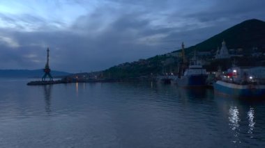 Denizin havadan görünüşü, eski paslı gemiler, vinçler, kilise ve Petropavlovsk-Kamçatsky 'nin yeşil tepeleri. Kamçatka Yarımadası 'na git..