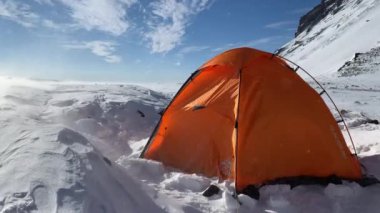 KAMCHATKA PENINSULA, RUSSIA - 11 Eylül 2020: Vahşi rüzgarda ekstrem bir turuncu çadır duruyor. Kamçatka Yarımadası 'na git. 3000 metre yükseklikte şiddetli bir kar fırtınası..