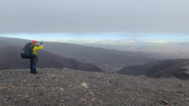 Sırt çantalı bir turist telefonuyla Kamçatka 'nın doğasının fotoğraflarını çekiyor. Kamçatka 'da gezi. Kamçatka Yarımadası 'na git..