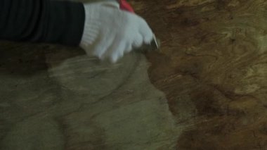 Bir adam eski ahşap bir masayı cilalıyor. Ellerinizi koruyucu eldivenlerle kapatın. Boya işi işe yarıyor. Mavi sivilceli ve sarı kenarlı beyaz eldivenler..