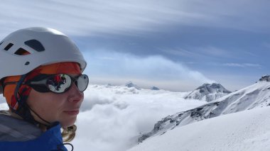 Güvenlik kaskı ve güneş gözlükleriyle dağın tepesine tırmanan mutlu dağcı. Kamçatka volkanları. Kamçatka Yarımadası 'na git..