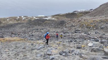 Gezginin üç turisti Kamçatka 'nın taş kalıntıları boyunca yürüyorlar. Klyuchevskoy volkan parkında gezinti. Kamçatka Yarımadası 'na git..