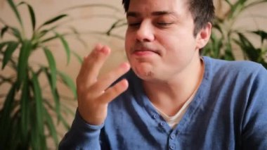 Mavi kazaklı karizmatik bir adam lezzetli bir yemekten sonra parmaklarını yalıyor. Yakın plan..