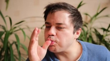 Genç adam lezzetli bir yemekten sonra parmaklarını yalıyor, eliyle ağzını siliyor ve rahatlıyor. Yakın plan..