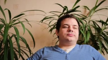 Genç bir adam lezzetli bir yemekten sonra rahat oturur. Doygunluk, öğle yemeği, keyif. Arka planda yeşil bitkiler.