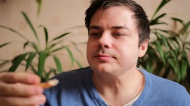 Genç bir adam ağzına bir dilim vejetaryen pizza atar ve onu gazozla içer. Yakın plan..