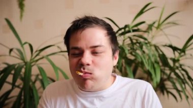 Yakışıklı bir adam büyük bir zevkle lezzetli bir peynirli pizza yer ve onu gazozla içer. Genç adam bir dilim pizza alır ve bir ısırık alır. Arka planda yeşil bitkiler.