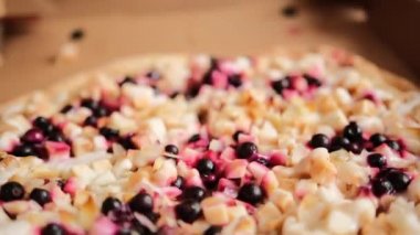 Elma parçaları, böğürtlen, badem dilimleri ve karton kutuda yoğunlaştırılmış sütle dolu büyük yuvarlak pizza turtası. Erkek eller iki dilim tatlı pizza alır. Yakın plan..