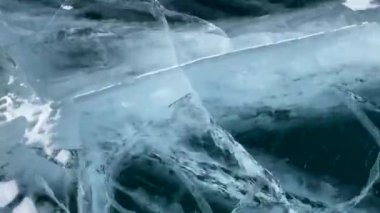 Baykal Gölü 'nde hızlı kayak. Derin çatlakları olan mavi şeffaf buz. Rusya 'nın doğal simgesi. Temiz ve pürüzsüz buzla güzel bir kış manzarası.