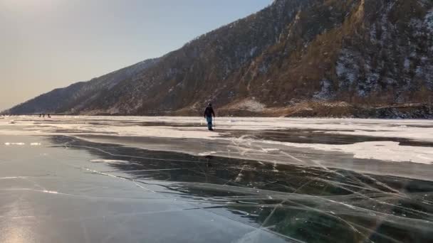 파란색 바지를 선글라스 아이스 스케이트 얼어붙은 바이칼 호수의 위에서 뒹굴고 — 비디오