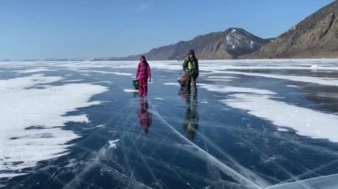 Kasklı bir adam ve sırt çantalı bir kız donmuş Baykal Gölü boyunca seyahat ediyorlar. Derin çatlakları ve kar adaları olan şeffaf mavi buzla güzel bir kış manzarası. Olkhon Adası.