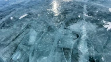 Adam donmuş Baykal Gölü 'nün şeffaf mavi buzunu kırıyor. Buz kütlesi birçok parçaya ayrılır. Derin çatlakları olan güzel buz..