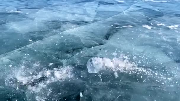 慢动作视频 一个家伙打破一块冰在光滑透明的蓝色冰冻结的贝加尔湖 浮冰碎裂成许多碎片 美丽的冰和深深的裂缝 — 图库视频影像